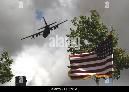 Un C-130 Hercules vola sopra la bandiera americana alla cerimonia commemorativa di Iron Mike il 7 giugno a la Fiere, Francia. Centinaia sono venuti per onorare coloro che hanno sacrificato durante il D-Day e la seconda guerra mondiale 65 anni fa in questo stesso campo. Foto Stock