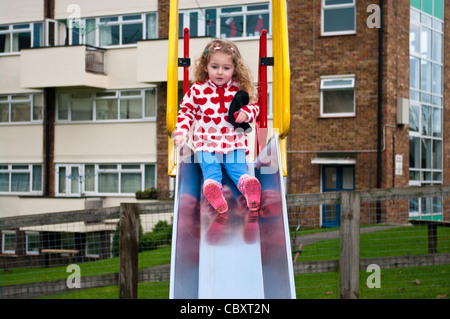 Bambino di 3 anni ragazza Neonato Bimbo giocando lo scorrimento verso il basso una diapositiva in un parco giochi per i bambini Foto Stock