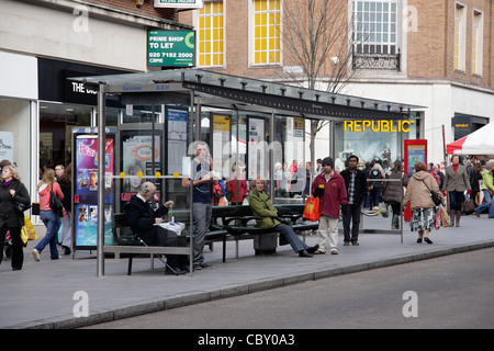 Le persone in attesa di una coda di Bus in coda per fermate e gli autobus in Exeter High St UK Foto Stock