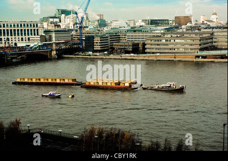Rimorchiatore tirando il traffico merci su chiatte attraverso il centro di Londra lungo il Tamigi Foto Stock