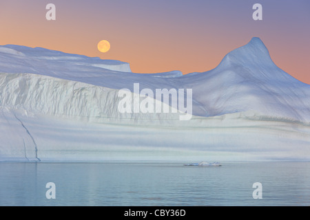 Iceberg al tramonto e il sorgere della Luna a Hall Bredning, Scoresbysund, Groenlandia Foto Stock