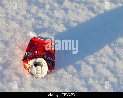 A Winter , Finlandia, la chiocciatura isolata di una birra rossa schiacciata giace sulla neve Foto Stock