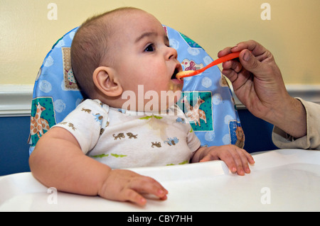 Otto mesi di età bambino essendo alimentato ananas organico dal Padre che è appena tornato a casa dal lavoro Foto Stock