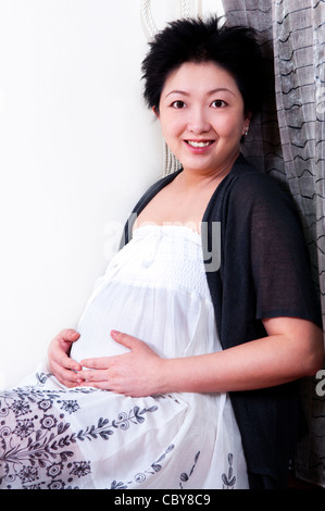 Asian donna incinta tenendo la mano sul ventre. Foto Stock