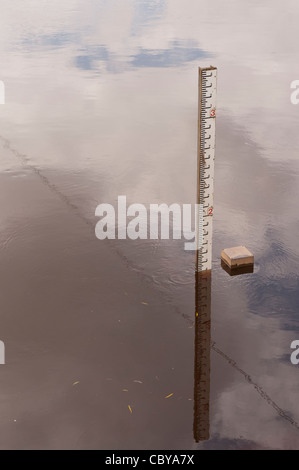 Un indicatore di profondità nel fiume Ouse, appena a nord di York, Regno Unito. Il cielo si riflette nel fiume. Foto Stock