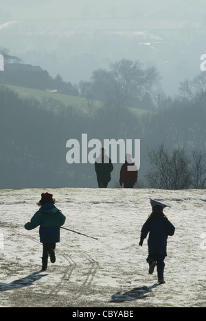 I bambini a giocare con i loro genitori su una coperta di neve hill Foto Stock
