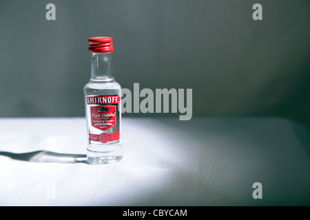 Bottiglia in miniatura di Smirnoff vodka in loco la luce sul tavolo bianco Foto Stock