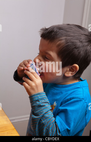 Giovane ragazzo tortini di mangiare da soli. Foto Stock