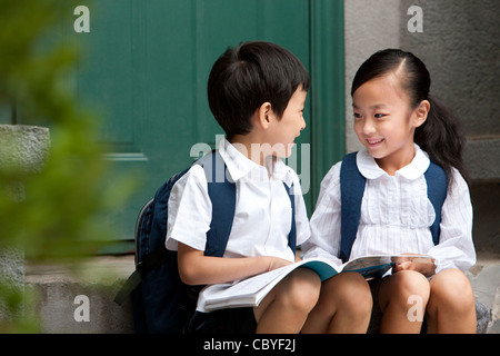 Scuola di due figli che studiano al di fuori Foto Stock