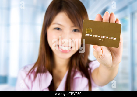 Donna asiatica in possesso di una carta di credito, focus sulla scheda. Il numero della carta di credito e data di scadenza creato dal mio. Foto Stock