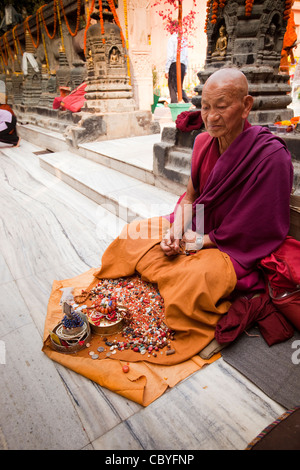 India, Bihar, Bodhgaya,, tempio di Mahabodhi, monaco utilizzando perle, pietre, il grano e le monete in euro per la meditazione buddista Foto Stock