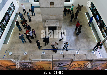 Mostra del muro di Berlino Newseum Washington DC // WASHINGTON DC - una vista dall'alto mostra i visitatori che esaminano la mostra del muro di Berlino di Newseum, che presenta otto sezioni originali in cemento del muro accanto a un'autentica torre di guardia della Germania Est. L'esposizione, vista dall'alto, mostra la scala di una delle più grandi collezioni di manufatti del muro di Berlino al di fuori della Germania. I turisti camminano tra il lato orientale aspro e la facciata occidentale ricoperta di graffiti dei segmenti murali conservati. Il Newseum chiuse nel 2019. Foto Stock