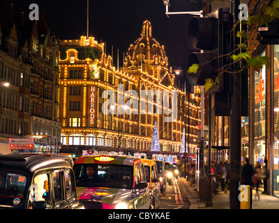 I grandi magazzini Harrods con le luci di Natale al tramonto con il taxi in attesa in linea.Knightsbridge Londra Inghilterra REGNO UNITO Foto Stock