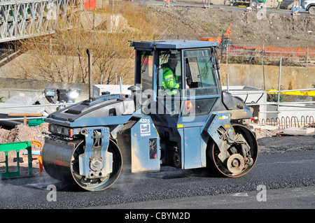 Uomo il rullo di guida sul lavoro fresco posate asfalto caldo superficie stradale Foto Stock