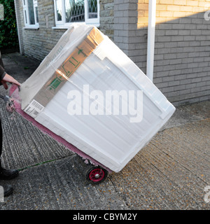 Uomo di consegna mediante carrello di servizio in grado di consegnare un nuovo Bosch asciugatrice dall apparecchio elettrico merci bianco retail business di alimentazione ad una casa in Inghilterra Essex REGNO UNITO Foto Stock
