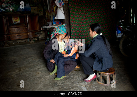 Femmina treni fisioterapista genitore a prendersi cura del bambino con handicap nella comunità basata del programma di risanamento in Vietnam. Foto Stock