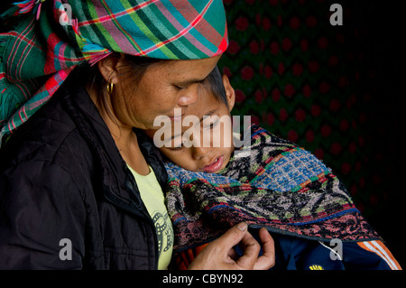 Ritratto di una madre dalla H'MONGS minoranza etnica in Vietnam con il suo bambino, una paralisi cerebrale (CP) del paziente. Foto Stock