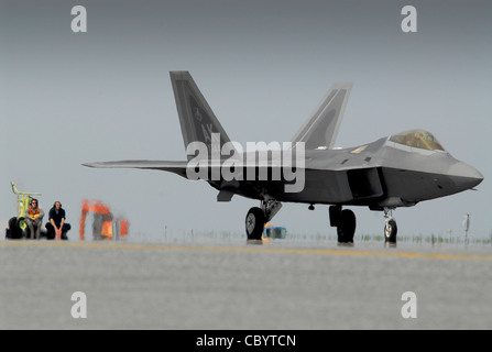 Gli airmen guardano come un F-22 Raptor taxi verso una stazione di rifornimento 31 marzo 2011, sulla linea di volo alla base aerea di Kadena, Giappone. I piloti e i manutentori, insieme alle F-22s, sono assegnati al 525esimo Squadrone Expeditionary Fighter presso la base congiunta Elmendorf-Richardson, Alaska. Si sono schierati a Kadena AB all'inizio del 2011 per testare le loro capacità in un nuovo ambiente e per allenarsi con Airmen e aerei. Foto Stock