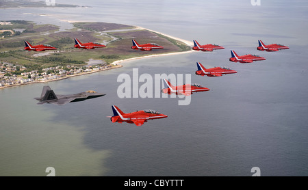 Un F-22 Raptor vola con la squadra aeronautica britannica Royal Air Force, le frecce rosse, durante un volo di prova del 18 giugno sulla base dell'aeronautica di Langley, Virginia, per un'esposizione aerea del 20 giugno. ( Foto Stock