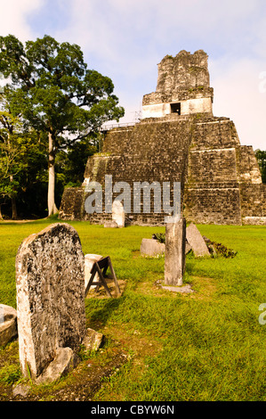 Tempio II Tempio delle Maschere Tikal Guatemala // TIKAL, Guatemala — Tempio II, il Tempio delle Maschere, sorge sopra una serie di stele intemprate sulla grande Plaza di Tikal. Le moderne scale in legno consentono ai visitatori di salire vicino alla cima di questa piramide di 125 metri, costruita intorno al 700 d.C. Il nome del tempio deriva dalle massicce maschere intagliate che una volta adornavano la sua facciata superiore, mentre l'intera struttura sarebbe stata originariamente dipinta in colori vivaci. Foto Stock