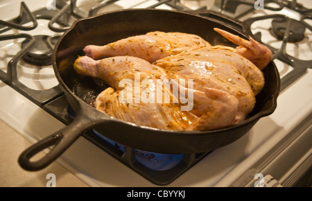 Dividere il pollo nella padella sul fornello a gas. Foto Stock