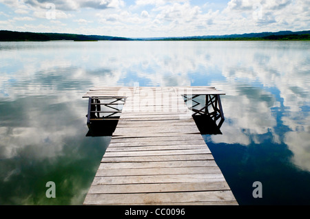 Lago Petén Itzá molo di legno Flores Guatemala // FLORES, Guatemala — Un molo di legno si estende nelle acque calme del lago Petén Itzá dalla città insulare di Flores nel nord del Guatemala. La pittoresca comunità lacustre è la capitale del dipartimento di Petén del Guatemala ed è collegata alla terraferma da una strada rialzata. Il lago Petén Itzá, che si estende per circa 32 chilometri quadrati, è il terzo lago più grande del Guatemala e riveste una significativa importanza ecologica e culturale nella regione. Flores è comunemente usato come base per i turisti che visitano le vicine rovine Maya di Tikal, situato app Foto Stock