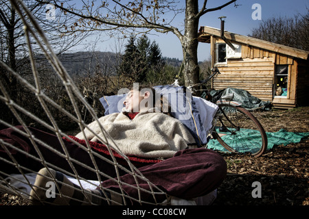 LORELEI prendendo un pisolino in una amaca, ha lasciato tutto alle spalle per venire costruire e vivere nella sua cabina di legno nella Creuse, Francia Foto Stock