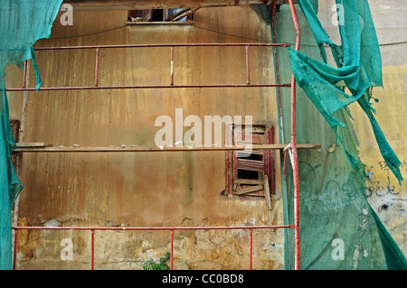 Edificio abbandonato con detriti strappati netting vetro rotto e grungy parete. Foto Stock