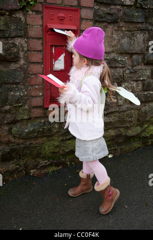 Un giovane bambino e bambina di cinque anni, inviare cartoline di Natale in un Royal Mail casella postale. Foto Stock