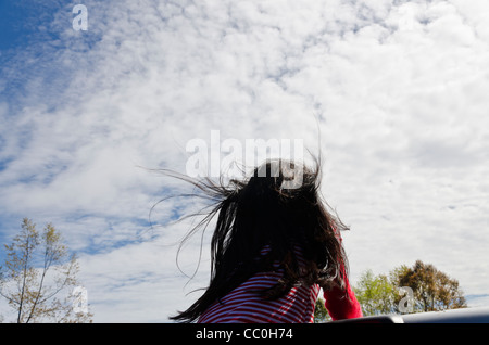 Lunghi capelli neri di una ragazza soffia il vento nel retro di un camioncino guida in Thailandia del Nord con sky in background Foto Stock