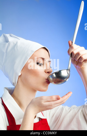 Lo Chef degustazione di zuppa di gusto dalla siviera su sfondo blu Foto Stock