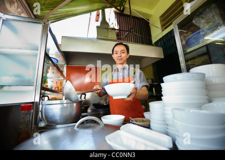 Lo chef prepara tradizionali asiatici street food e lavorare nella cucina del ristorante. Sagoma orizzontale, vista frontale Foto Stock