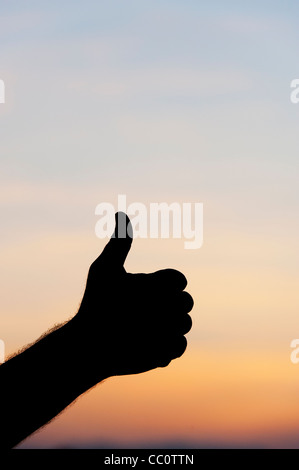 Thumbs up silhouette a mano contro il cielo di sunrise Foto Stock