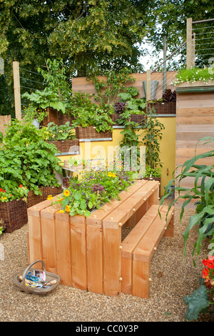 Tavolo in legno e panche in cucina cortile giardino con viveri e fiori in centro tavola. Foto Stock