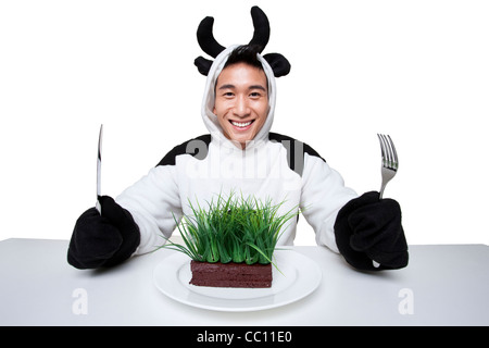 Uomo in una vacca costumi con un serving di erba sul suo piatto Foto Stock