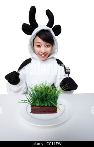 La donna in una vacca costumi con un serving di erba sulla sua piastra Foto Stock