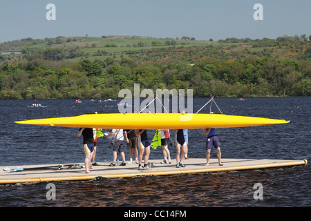 La squadra di canottaggio su un molo che solleva un doppio scull per metterlo in acqua, Regno Unito Foto Stock