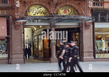 Motion Blured Police Officer passando l'ingresso alla Argyll Arcade, Buchanan Street, Glasgow centro città, Scozia, Regno Unito Foto Stock