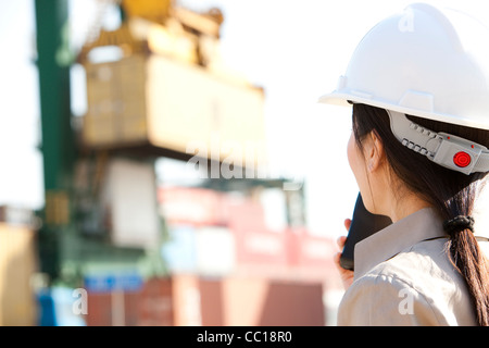 Industria marittima lavoratore dirigere le gru con il suo walkie-talkie Foto Stock