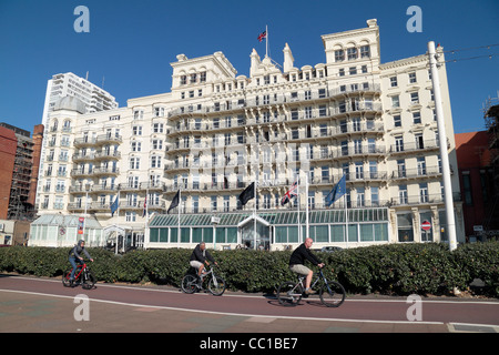 I ciclisti sul lungomare passare il Grand Hotel su Kings Road, Brighton Seafront, East Sussex, Regno Unito. Foto Stock