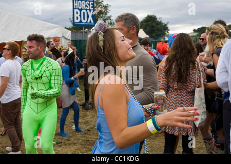 Una donna con una lattina di birra e una sigaretta balli in un campo per un mobile sistema audio a Standon Calling Festival Foto Stock