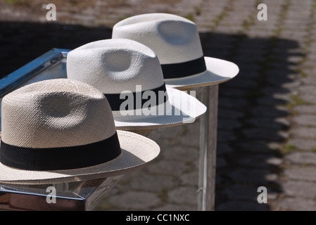 Tre Panama cappelli seduto su un contatore con un pattern sul terreno da un'ombra di un tetto di tegole creando un forte elemento grafico. Foto Stock