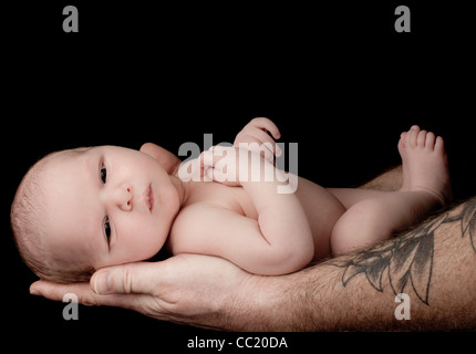 Neonato ragazzo essendo tenuto amorevolmente da suo padre. Foto Stock