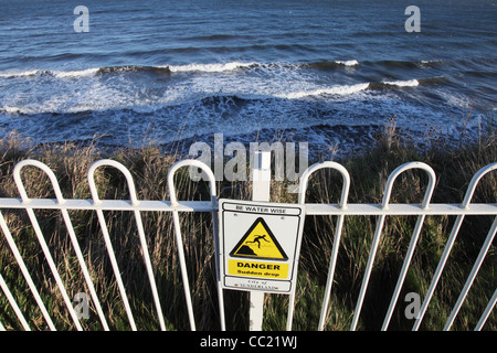 Segno o avviso di pericolo di caduta improvvisa, essere acqua Wise, sopra le scogliere Roker North East England, Regno Unito Foto Stock