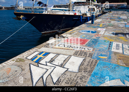 Una visita di yachtsman mano-dipinge una nave's calling card sulla marina di pareti a Horta, isola di Faial nelle Azzorre Foto Stock