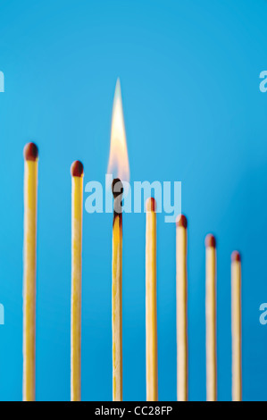 Un fiammifero che brucia in una fila di partite non illuminato Foto Stock