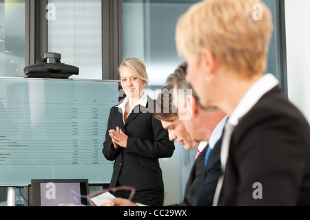 Azienda - Presentazione all'interno di un team; una femmina, collega è in piedi sullo schermo Foto Stock