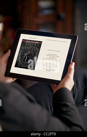 Vista ravvicinata di una donna in relax il soggiorno durante la lettura 'giochi di troni' sul suo iPad 2 Foto Stock