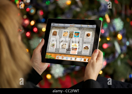 Vista ravvicinata di una donna tenere per mano le persone un ipad 2 controllo di ricette di cucina durante la vacanza di Natale Foto Stock