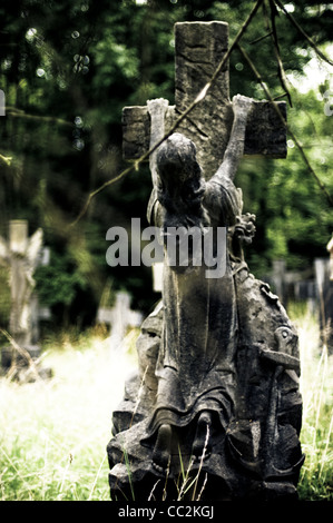 Statua di una giovane ragazza il salto sulla croce nel cimitero. Foto Stock